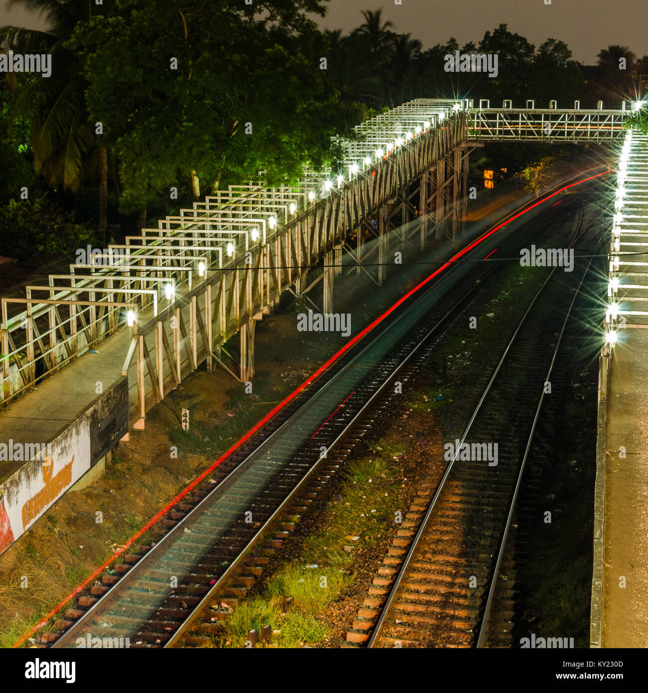 Nächtlicher Blick auf einen Zug, Bahnhof Madgaon unter einer Brücke zu gehen. Stockfoto