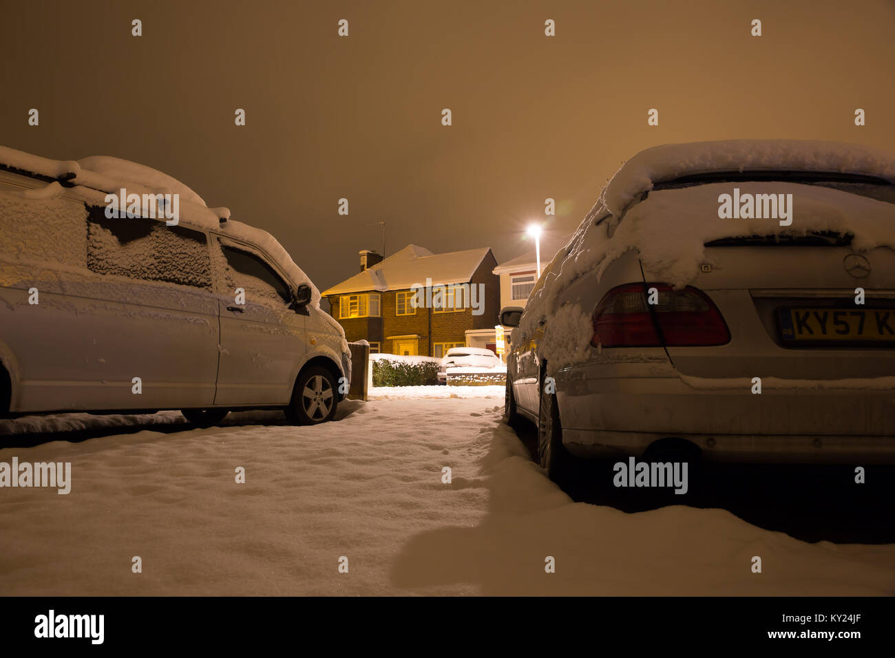 Verschneite Straße Szene auf einem kalten Dezember Abend, von der Einfahrt zu einem der Häuser. Auf der Suche nach weiß winter Straße bei Nacht. Stockfoto