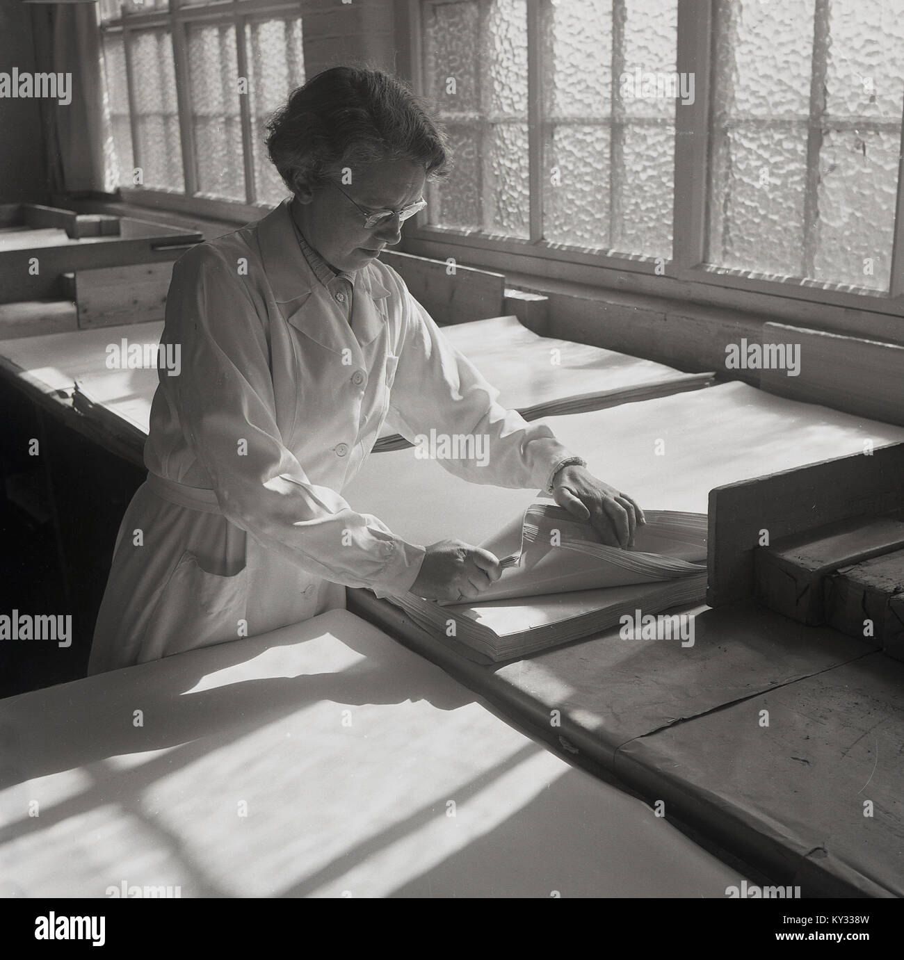 1950, historische, eine Arbeiterin Sortieren durch Keramik Seidenpapier auf brittains Limited, einem führenden britischen Papiermühle und Spezialpapierhersteller in Stoke-on-Trent, England, UK. Stockfoto