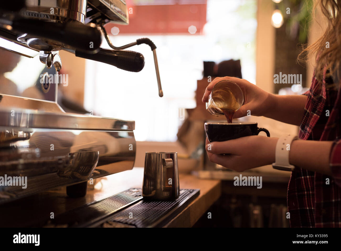 Den mittleren Abschnitt der Barista gießen Kaffee in Schale Stockfoto