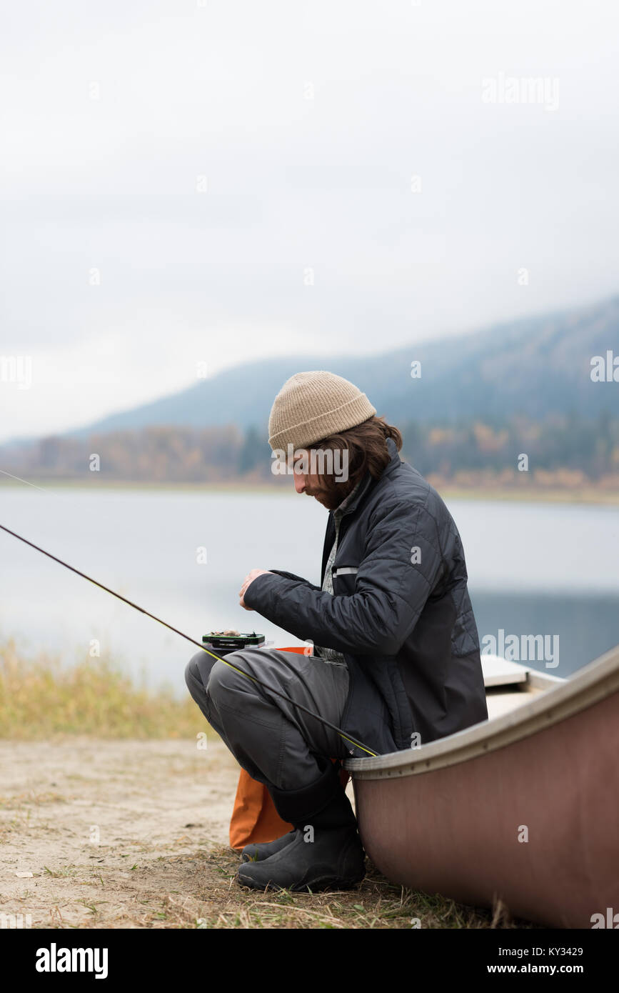 Mann sitzt auf dem Boot mit seiner Angelausrüstung Stockfoto