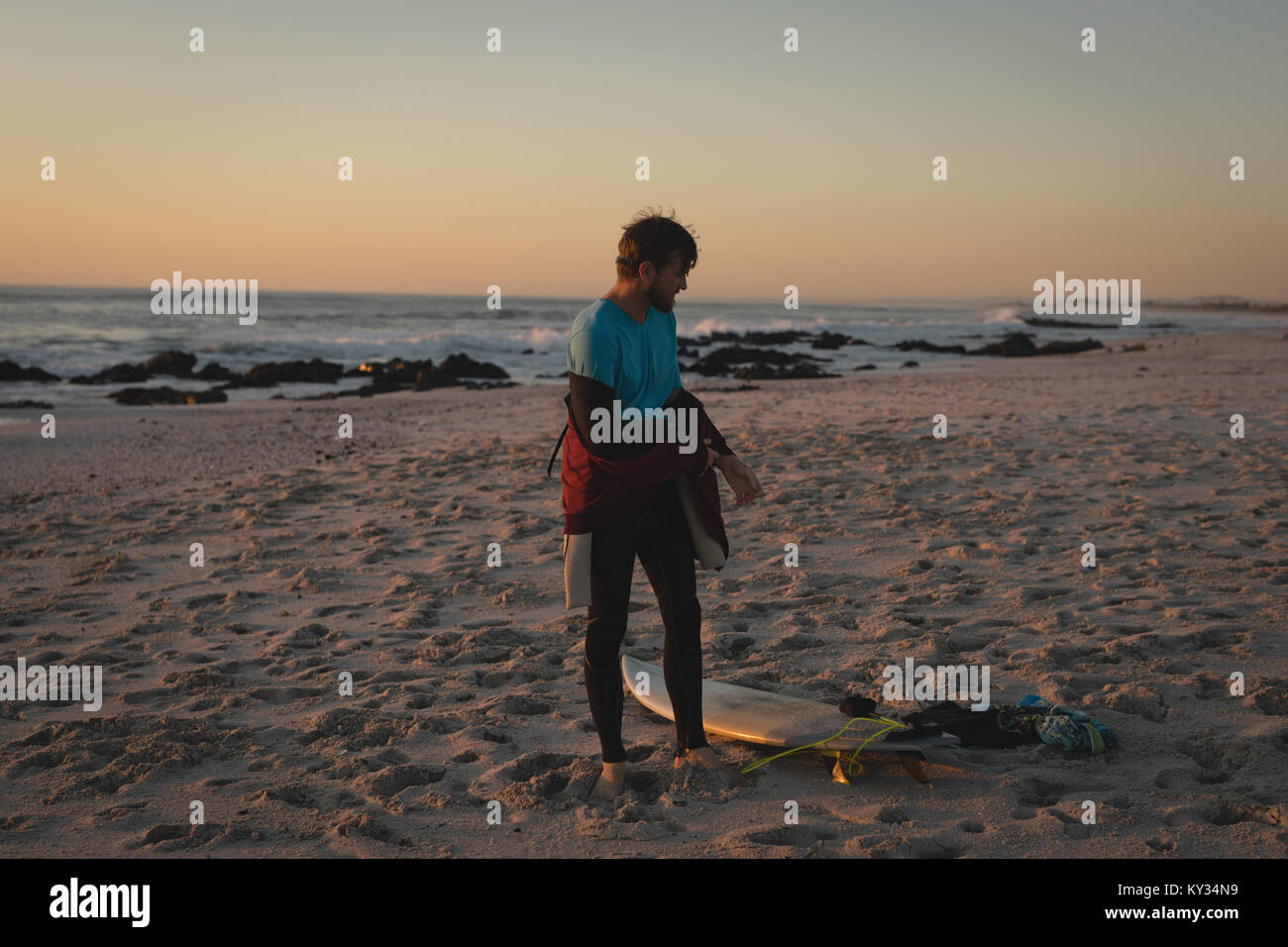 Surfboard entfernen Neoprenanzug am Strand Stockfoto