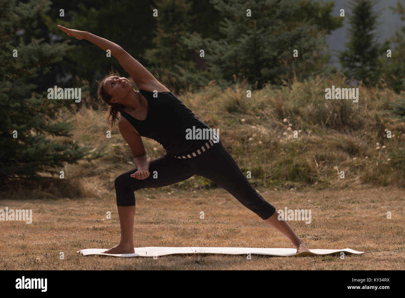 Passende Frau Durchführung stretching Übung auf offenen Boden Stockfoto