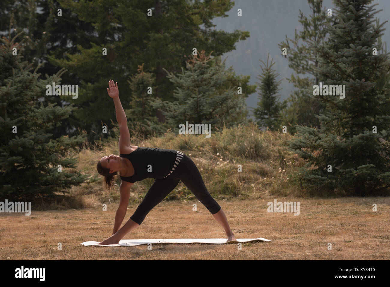 Passende Frau Durchführung stretching Übung auf offenen Boden Stockfoto