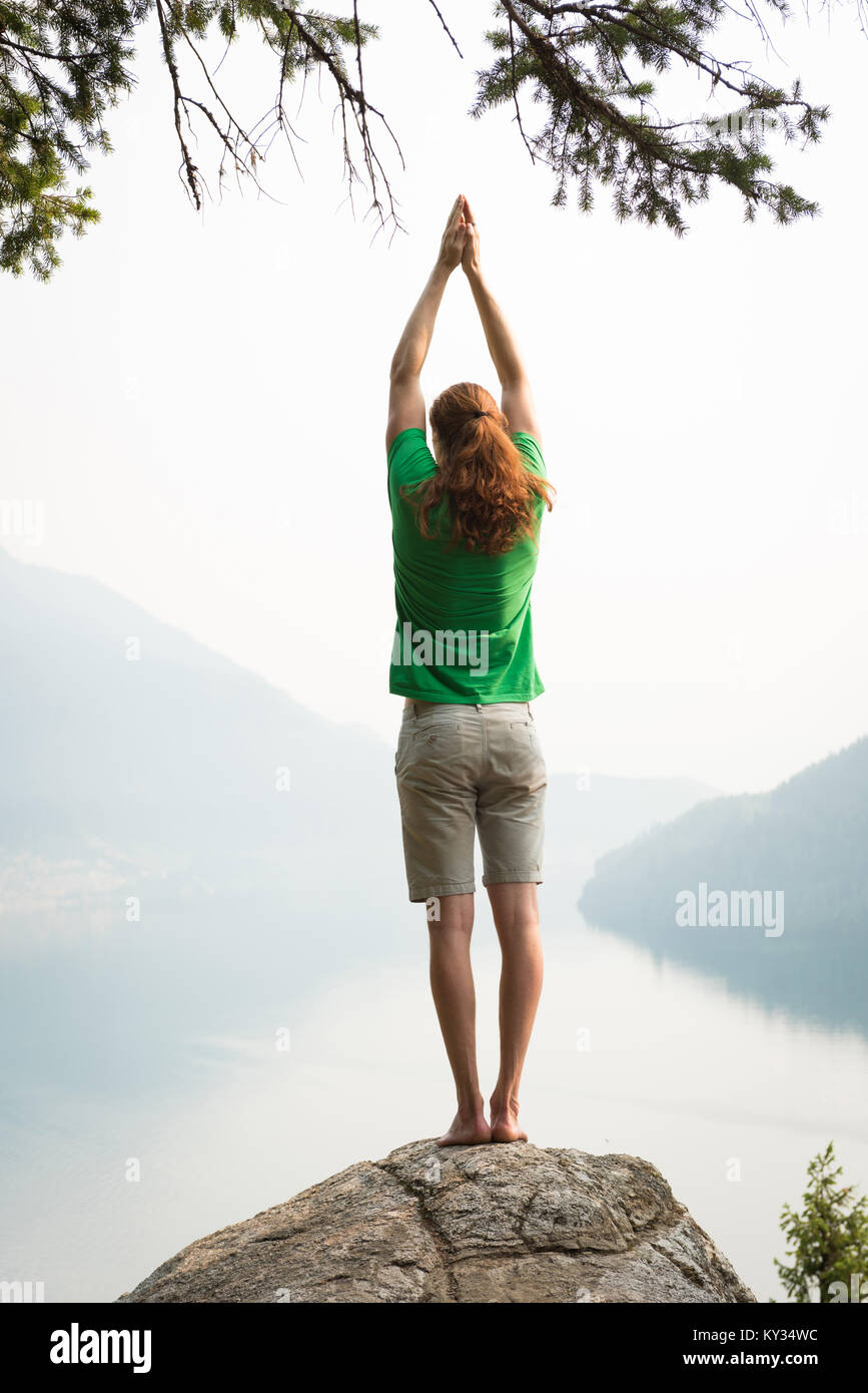 Passen mann Durchführung stretching Übung am Rande eines Rock Stockfoto