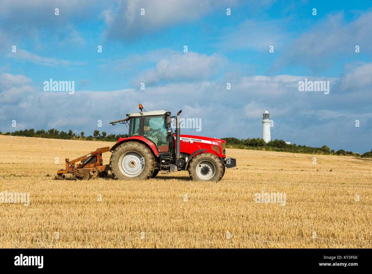 Roter Traktor in einem Feld neben Flamborough Leuchtturm, North Yorkshire, England. Stockfoto