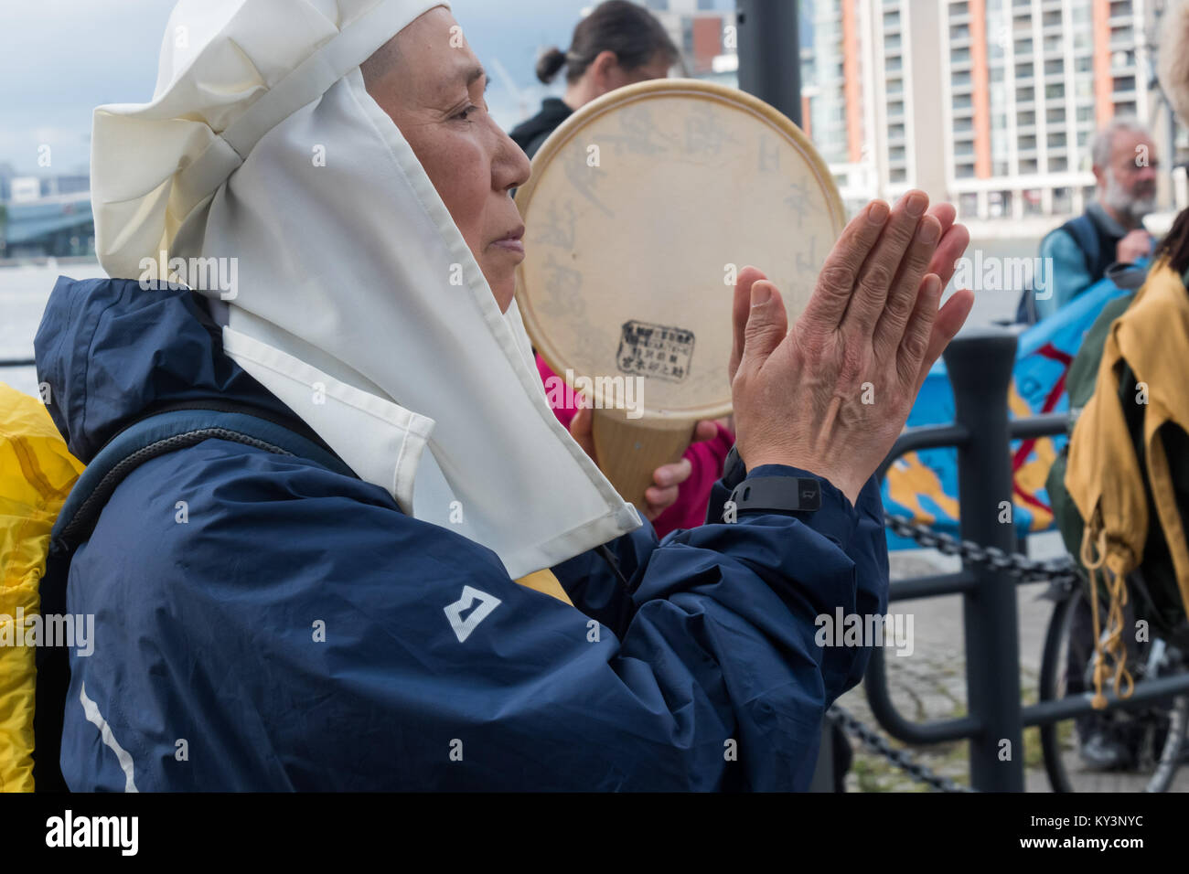 East London gegen den Waffen Messen Mitkämpfer beenden ihre Akt des Gedenkens für die Opfer der Waffen Messen mit einem Gebet von dem buddhistischen Reverend Nagase, wie sie die DSEi Arme fair über den Royal Victoria Dock. Stockfoto