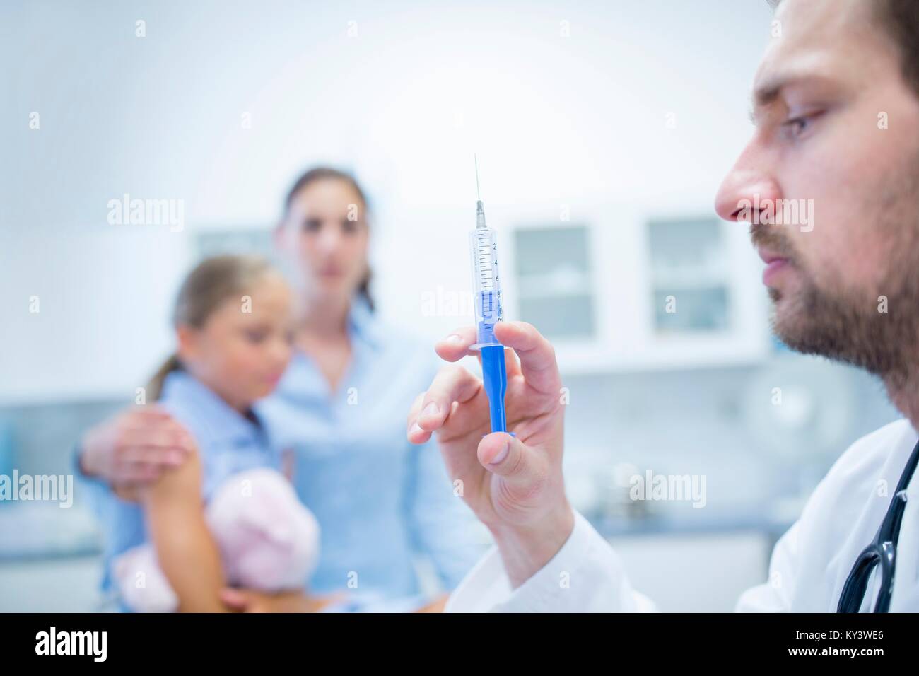 Arzt Vorbereiten der Injektion, junges Mädchen im Hintergrund. Stockfoto