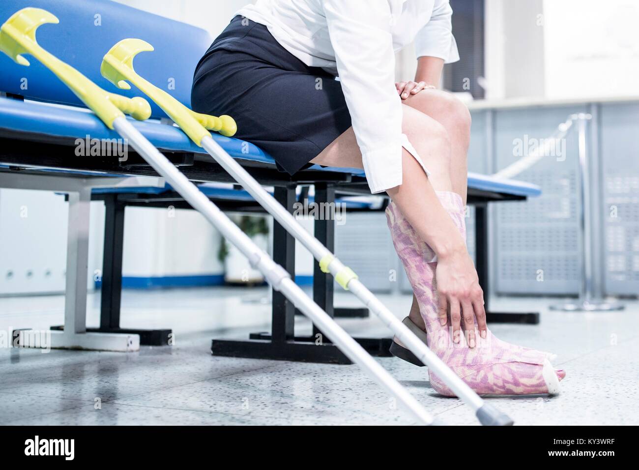 Frau mit Bein in Gips sitzen auf Stuhl mit Krücken Stockfotografie - Alamy