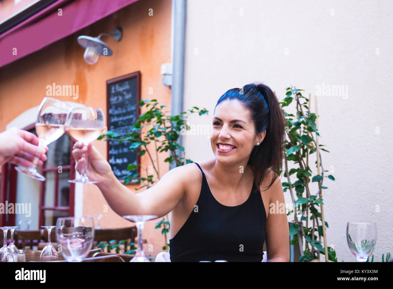 Schöne Frau an outside cafe Toasten mit Weinglas. Stockfoto