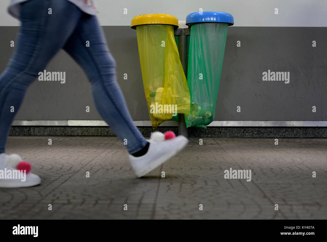 Pom poms Schuhe Spaziergänge in der Nähe von farbigen Taschen von Abfällen Stockfoto