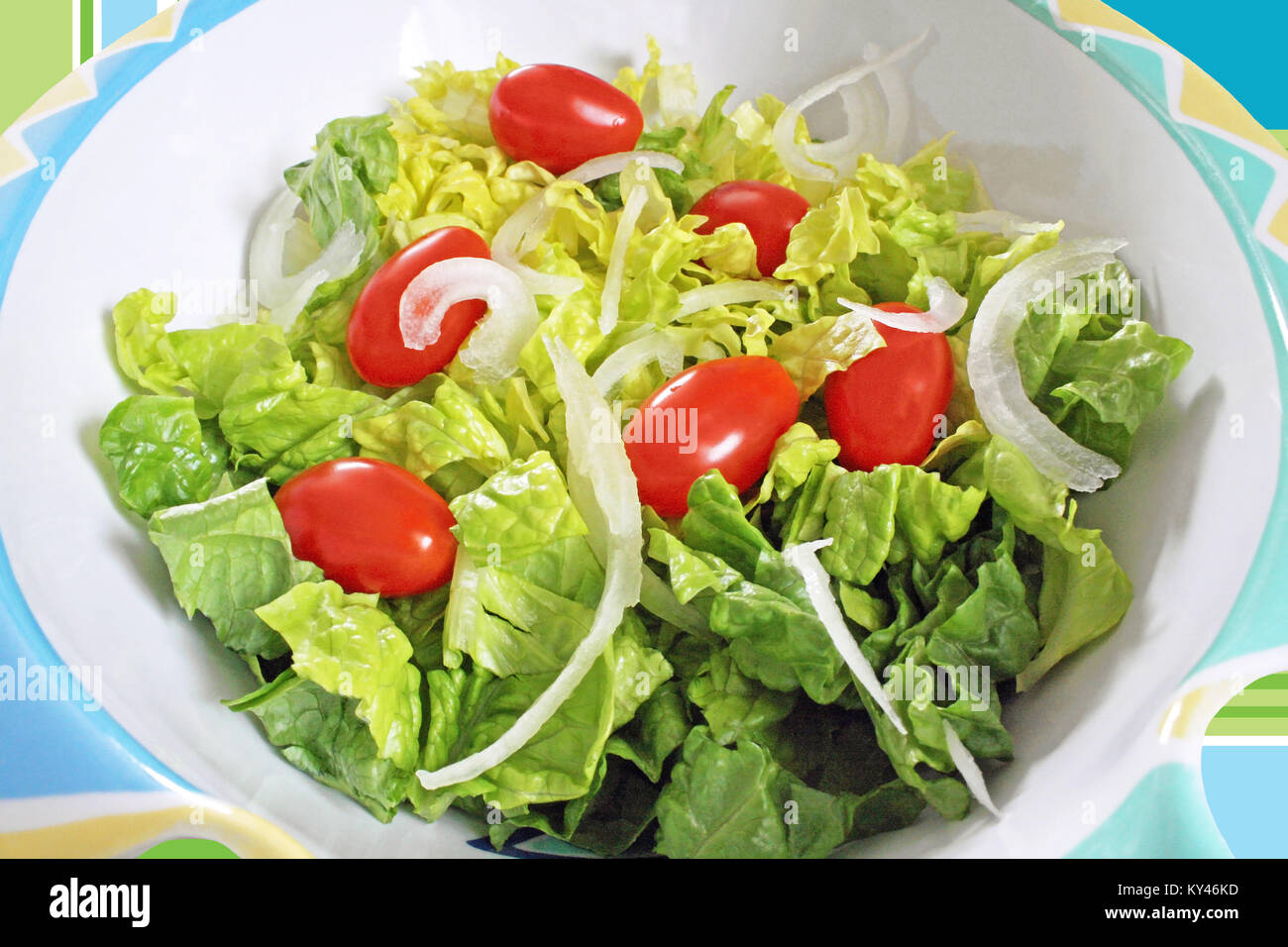 Frische gehackte Römersalat, reife Tomaten in Scheiben geschnitten und weiße Zwiebel in eine Bunte Salatschüssel Stockfoto