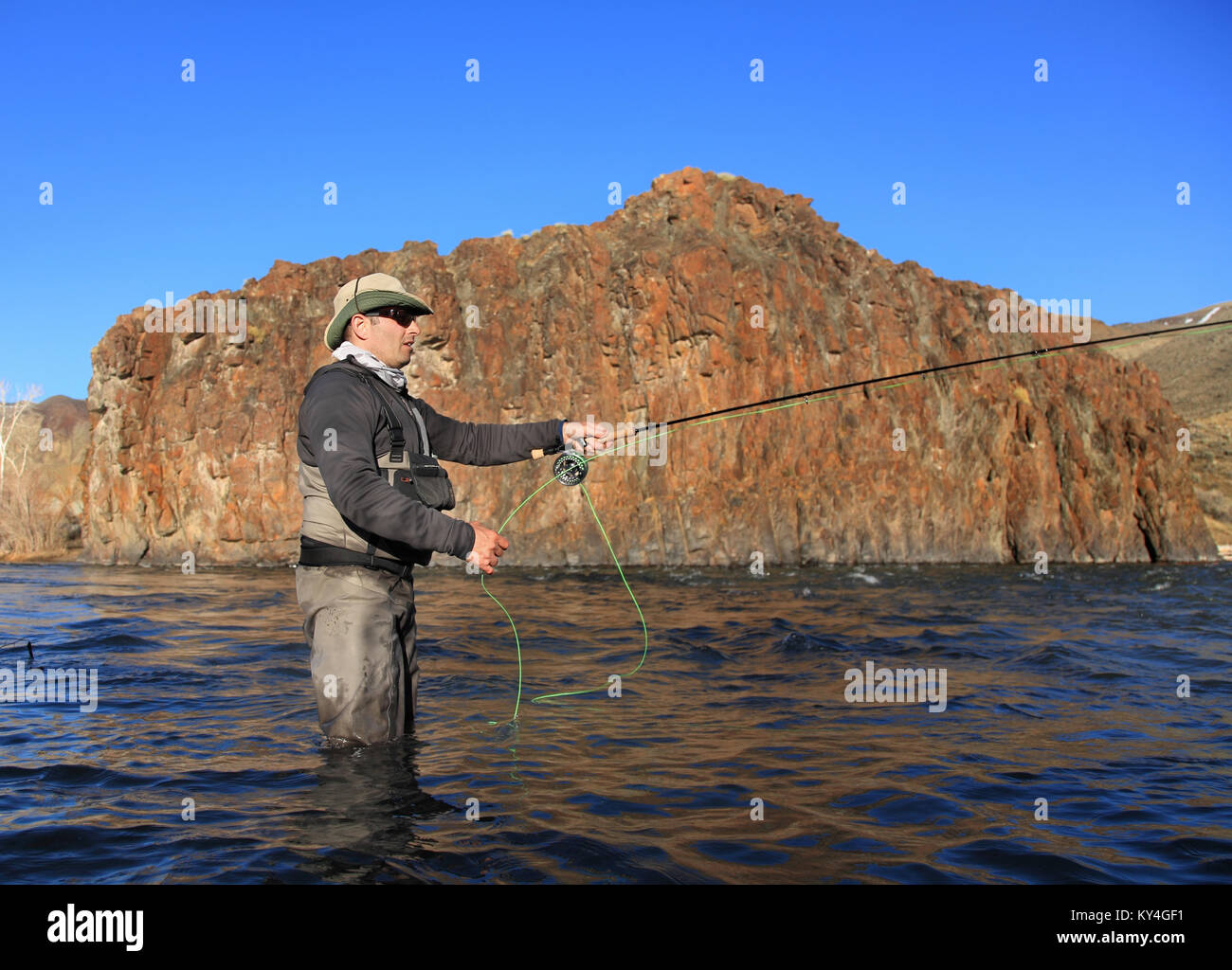Fliegenfischer Gießrute auf großen Fluss mit felsigen Hintergrund Stockfoto