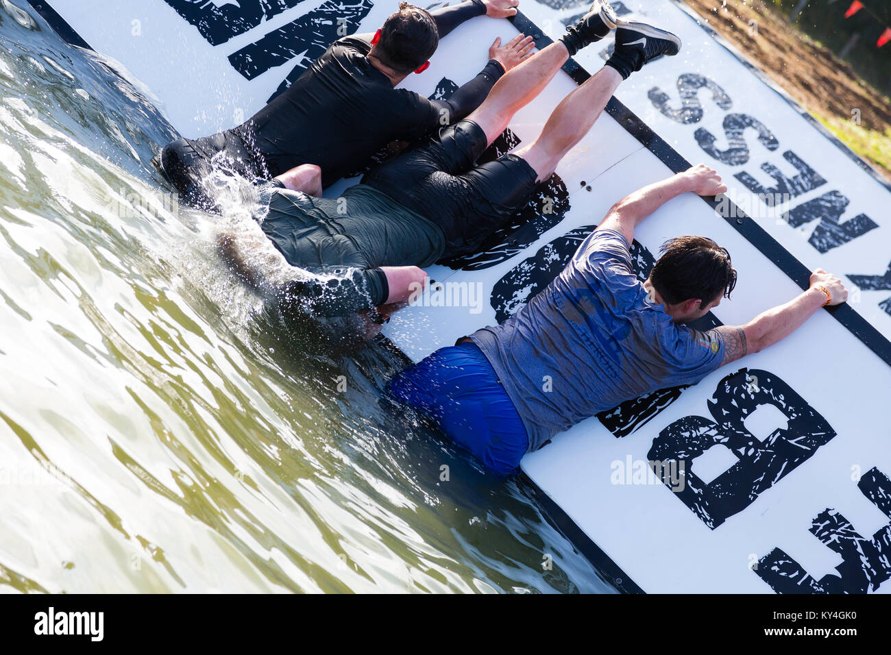 Sussex, UK. Ein Mann fällt kopfüber in einen Pool von Wasser auf dem Block Ness Monster Hindernis während einer haltbaren Mudder Ereignis. Stockfoto