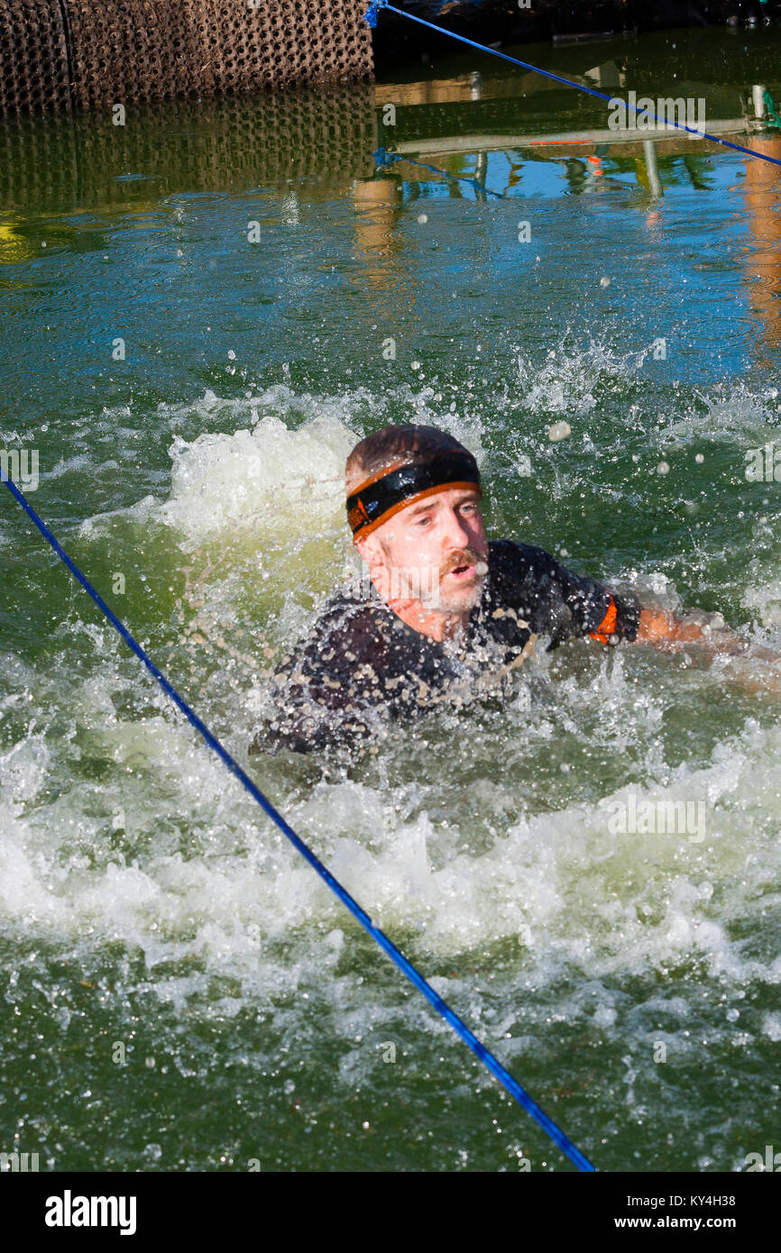 Sussex, UK. Ein männlicher Konkurrent schnappt nach Luft, als er Oberflächen, nachdem es in das Wasser auf harten Hindernis der Hangin' während einer haltbaren Mudder Ereignis. Stockfoto