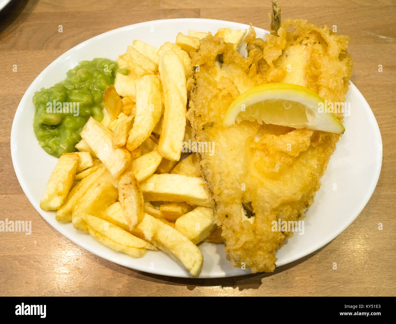 Eine Umhüllung von Scholle und Chips mit schönen Teig eine Scheibe Zitrone und Erbsenpüree, bereit zum Essen in ein Restaurant Stockfoto