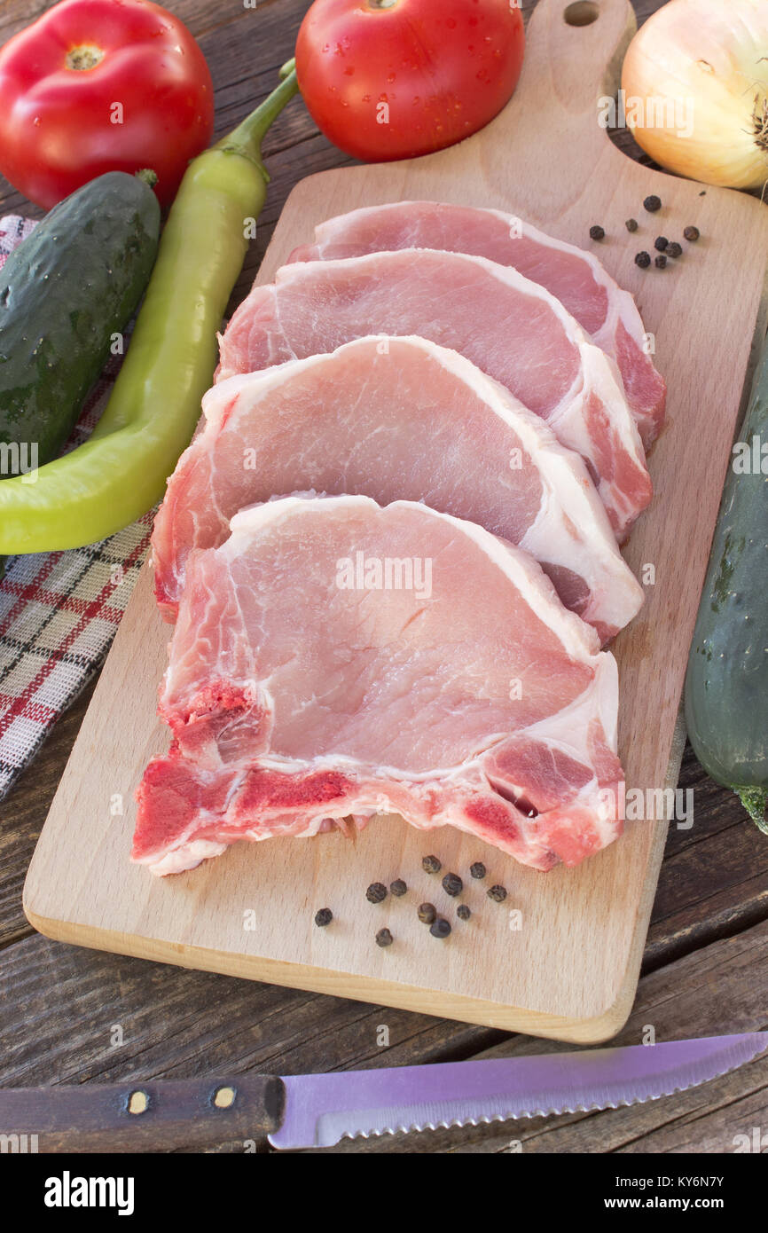 Rohes Schweinefleisch mit Gemüse auf Holztisch chop Stockfoto