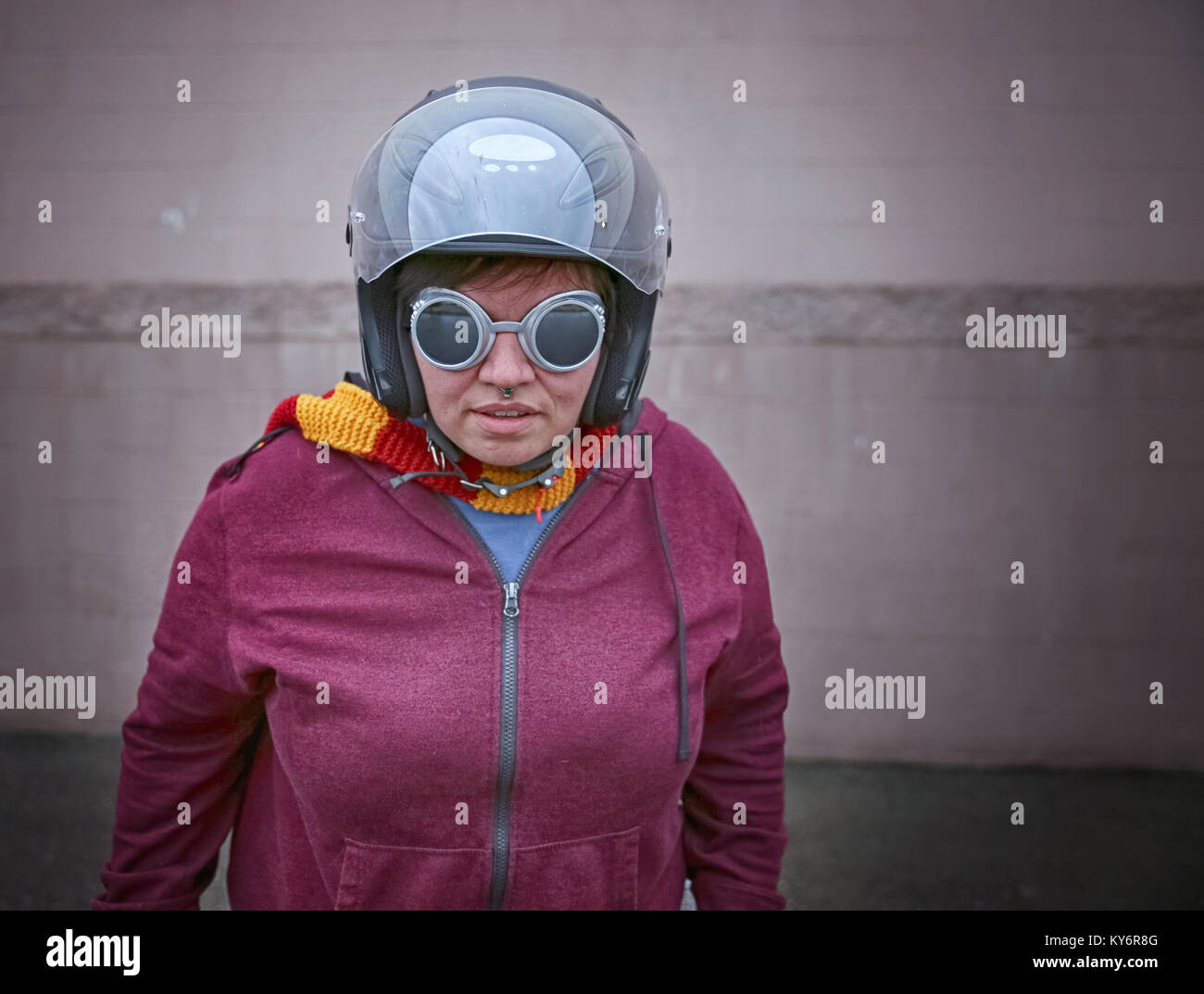Eine Frau in einem Motorrad Helm mit Steampunk goggles auf vor einer Wand getönt mit Retro Vintage instagram Filterwirkung app oder Aktion Stockfoto