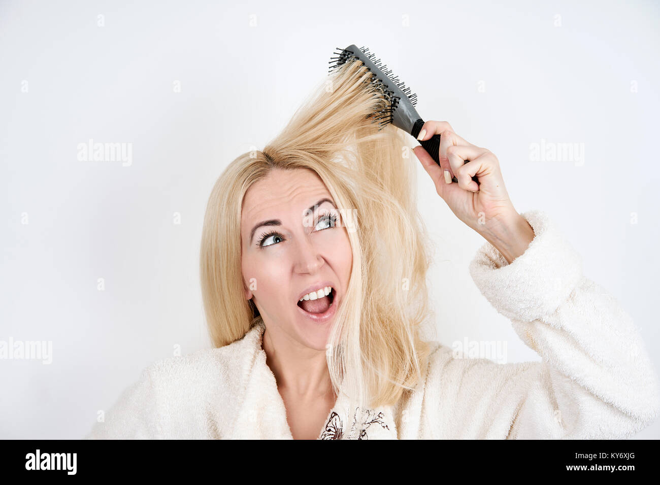Mädchen in einen Bademantel mit einer Haarbürste im Haar verfangen auf weißem Hintergrund Stockfoto