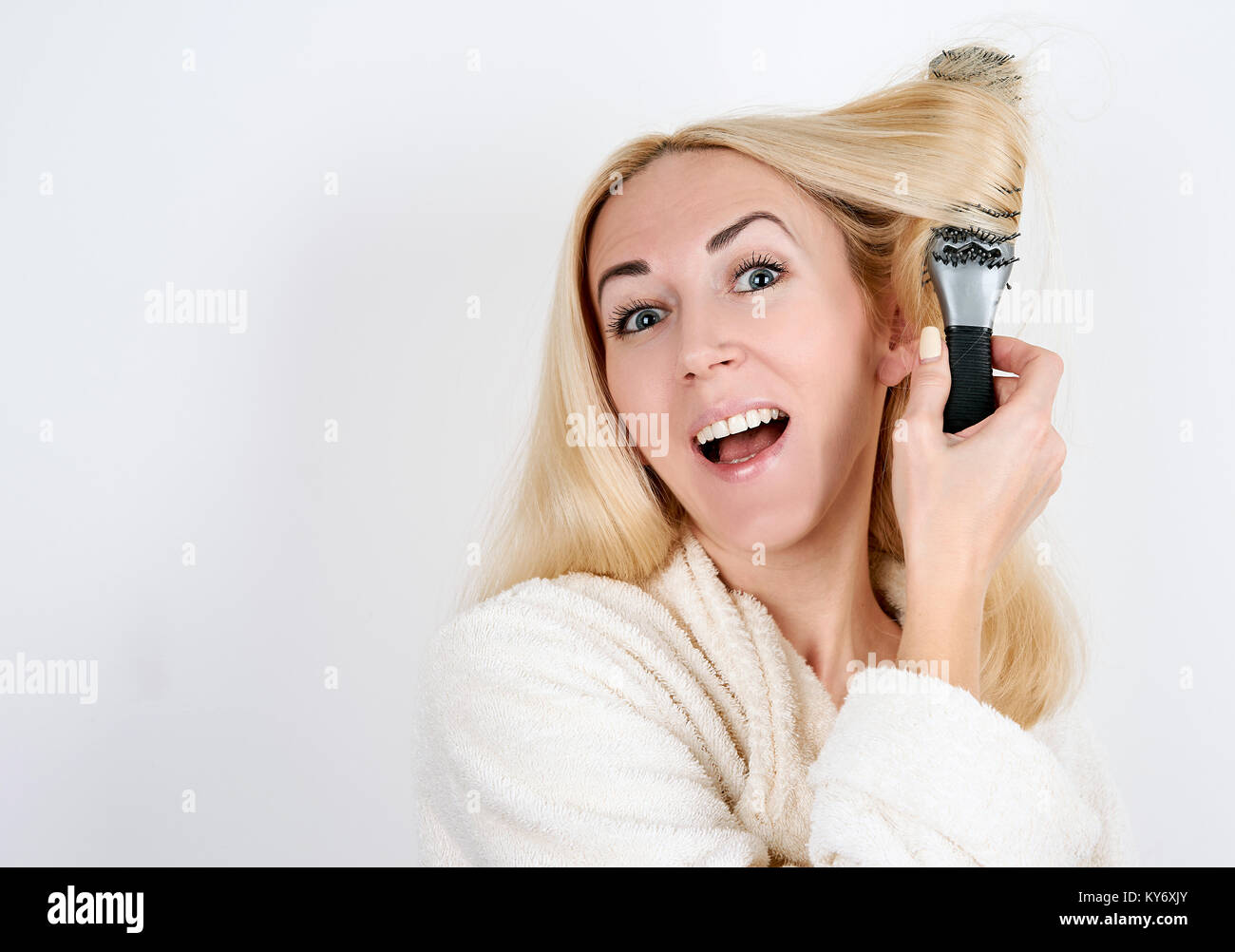Mädchen in einen Bademantel mit einer Haarbürste im Haar verfangen auf weißem Hintergrund Stockfoto