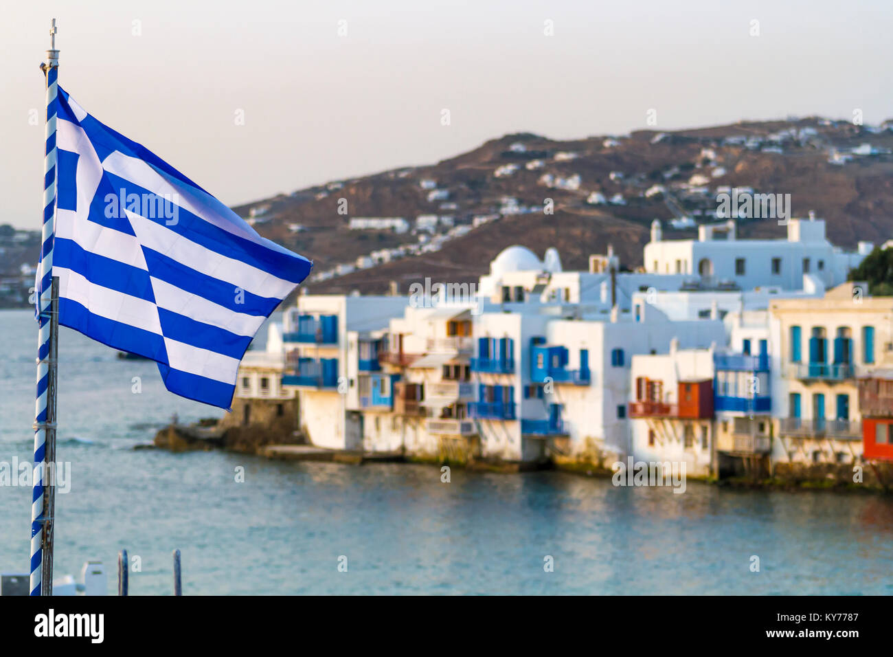 Griechische Flagge im Sommer Luft mit Blick auf den Sonnenuntergang aus Little Venice, Mykonos, Griechenland, Sommer 2017 widerspiegelt. Stockfoto