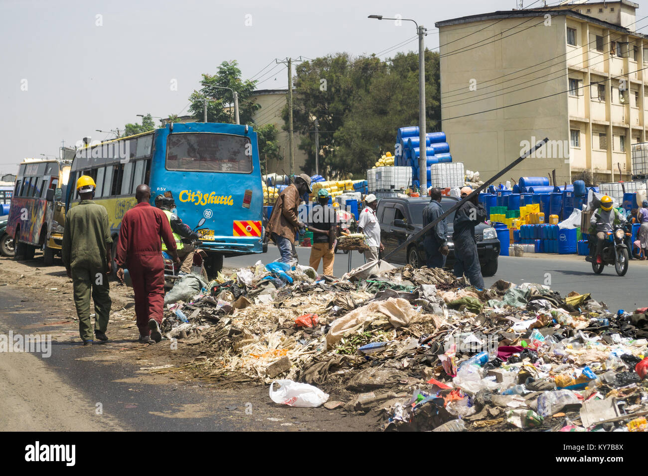 Einen großen Haufen von plastik Müll und anderen Abfällen sitzt in der Mitte der Straße als Menschen und Fahrzeuge Vergangenheit gehen, Nairobi, Kenia, Ostafrika Stockfoto