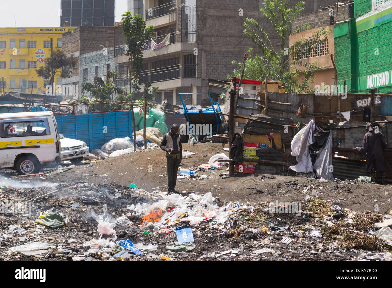 Ein Mann steht neben einem großen Haufen Müll mit einem kleinen Feuer brennen, Nairobi, Kenia, Ostafrika Stockfoto