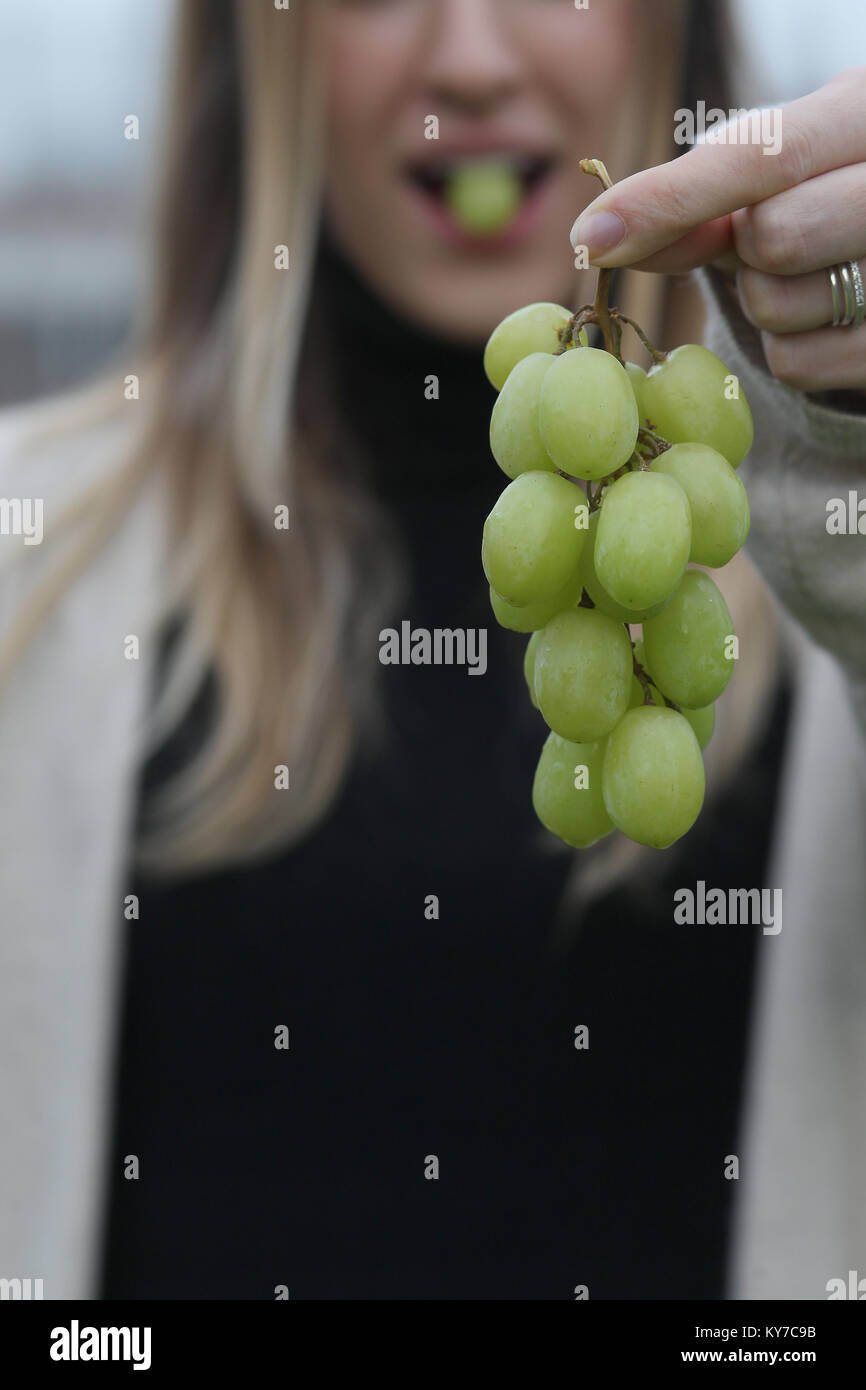 In Spanien ist es eine Tradition zwölf Trauben für das Neue Jahr zu essen. Eine junge Frau isst Trauben, die an Silvester in Spanien. Stockfoto