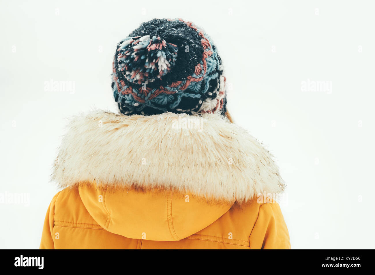 Winter Frau alleine im Freien warme Kleidung pelz Kapuze Mantel Mode Lifestyle weißen Schnee Hintergrund Rückansicht Stockfoto