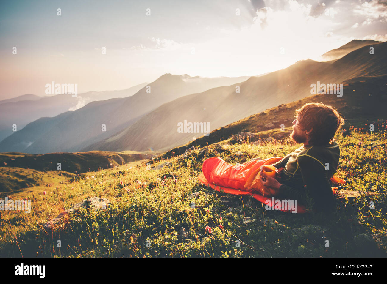 Man Relaxen im Schlafsack genießen Berge Sonnenuntergang Landschaft Reisen Lifestyle camping Konzept Abenteuer Sommer Urlaub Outdoor wandern mountainee Stockfoto