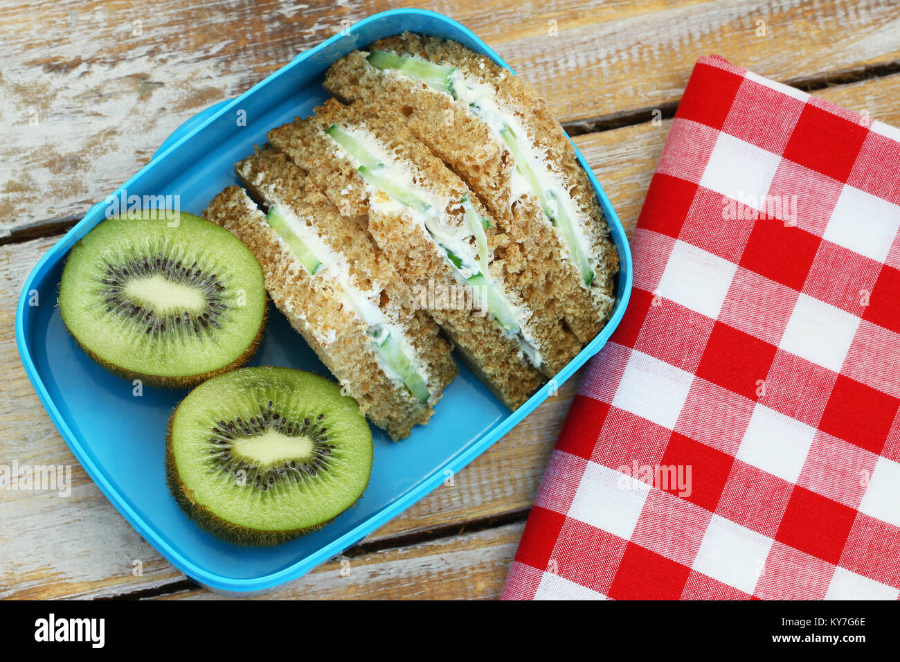 Brown Cream Cheese Sandwiches mit Gurke und Kiwi in Lunch Box Stockfoto