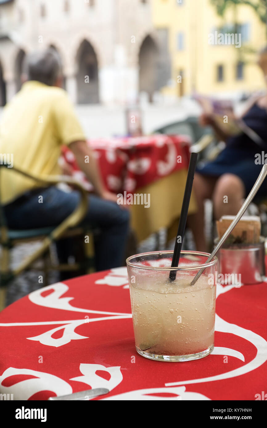 Ein Glas kaltes Zitrone alkoholfreies Getränk mit Würfeln aus Eis auf einer roten Tischdecke in open Air Cafe auf eine historische Straße. Stockfoto