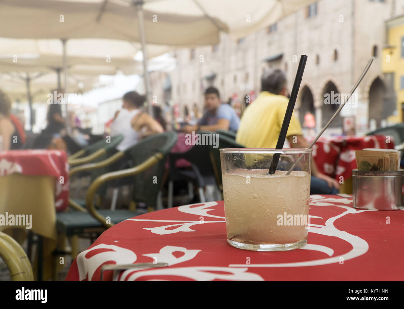 Ein Glas kaltes Zitrone alkoholfreies Getränk mit Würfeln aus Eis auf einer roten Tischdecke in open Air Cafe auf eine historische Straße. Stockfoto