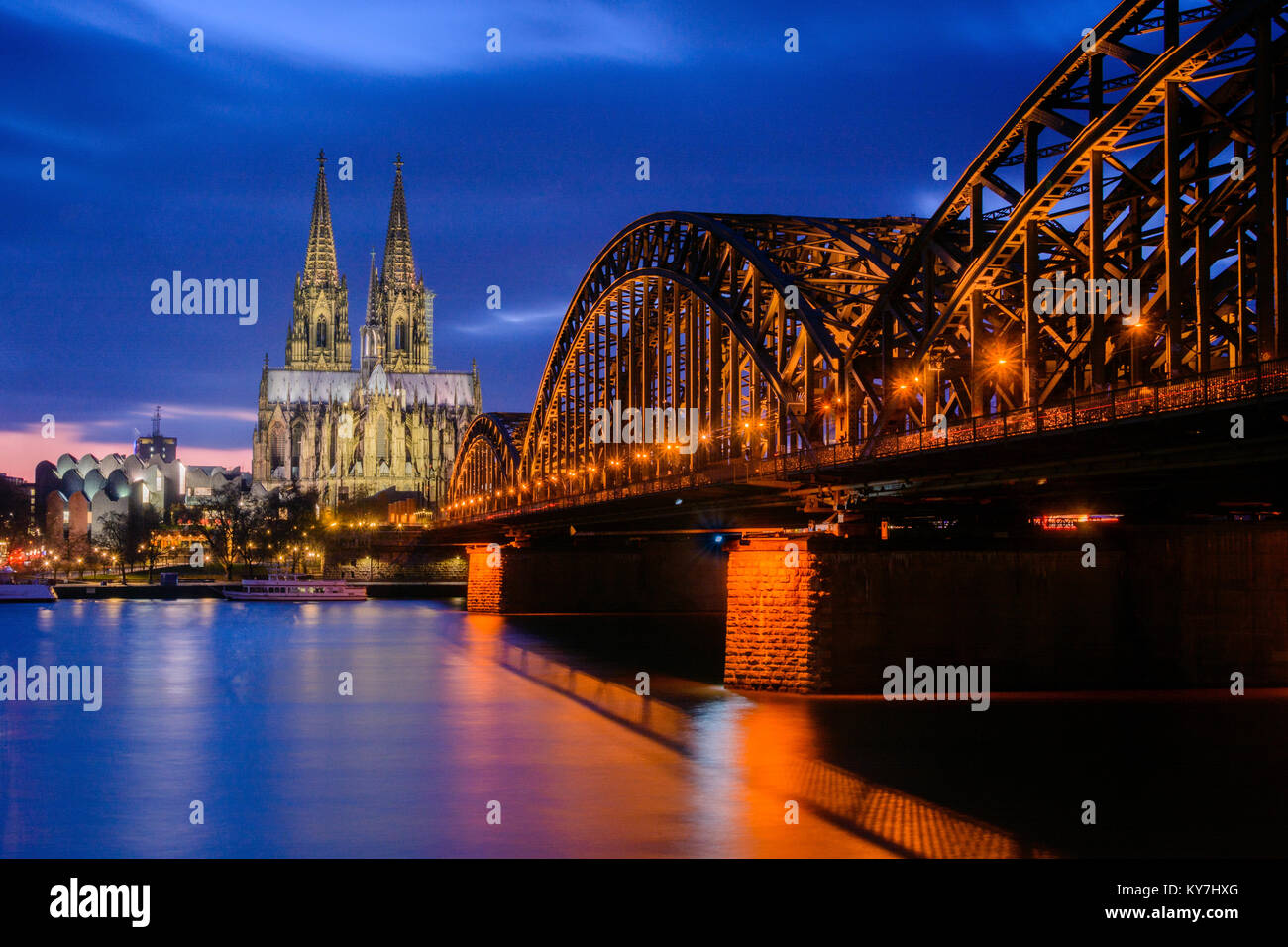 Kölner Dom (Dome) in Deutschland an der Blauen Stunde, Hohenzollern Brücke auf der rechten Seite Stockfoto