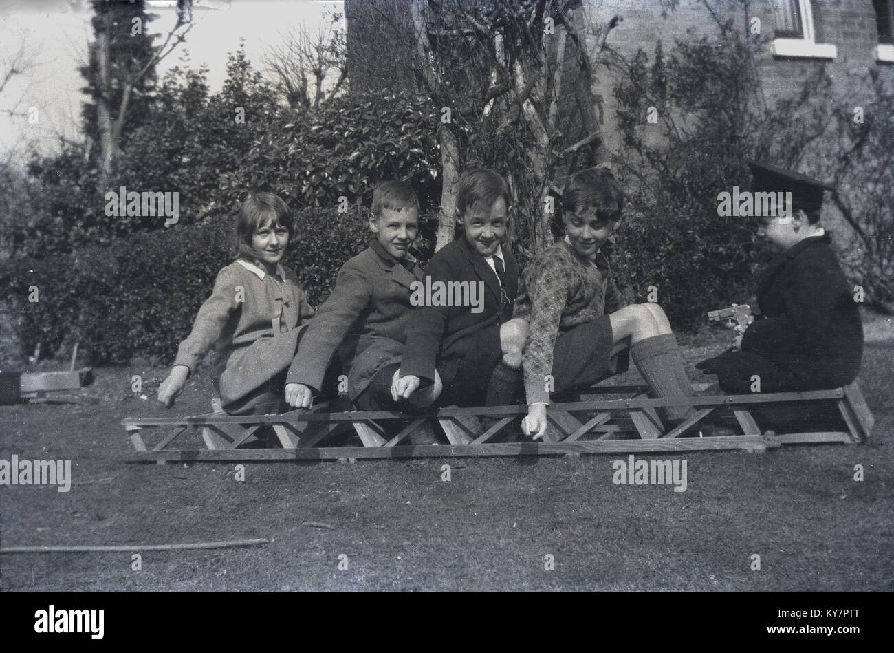 1930er Jahre, historische, Jungen und ein Mädchen ihren eigenen Spaß, Bus Spiele wie auf einer Holzleiter draußen im Garten, England, UK. Stockfoto