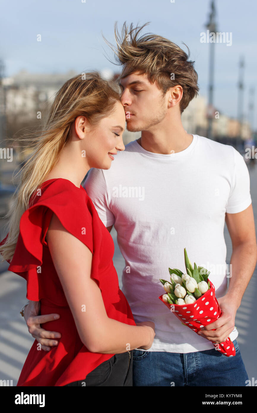 Junges Paar mit weißen Tulpen Blumenstrauß im Freien, Hug am Valentinstag Stockfoto