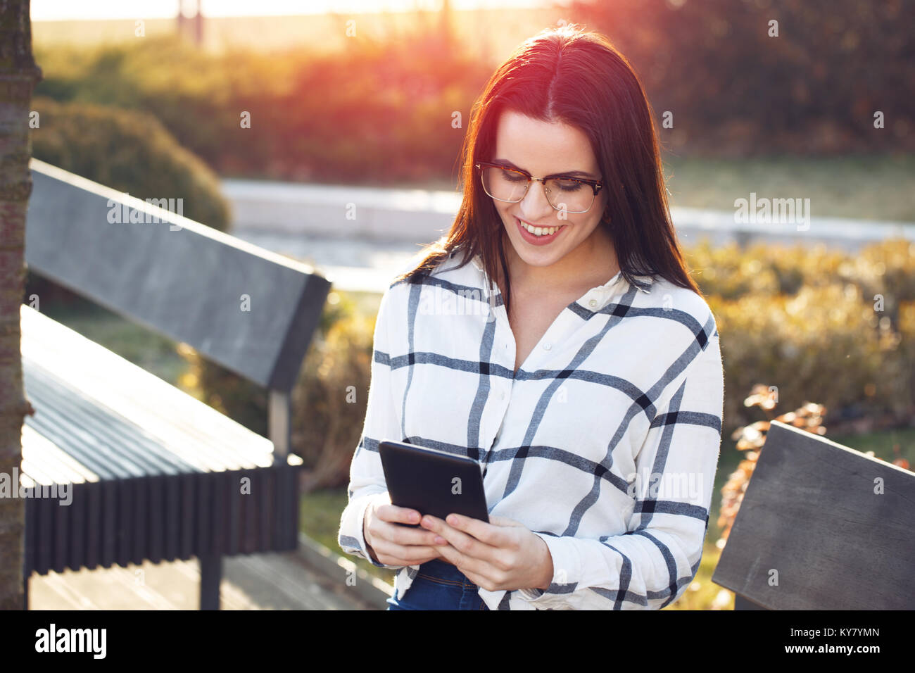 Smart Casual Frau in Gläser mit Tablet Outdoor im Park im Sonnenuntergang Stockfoto