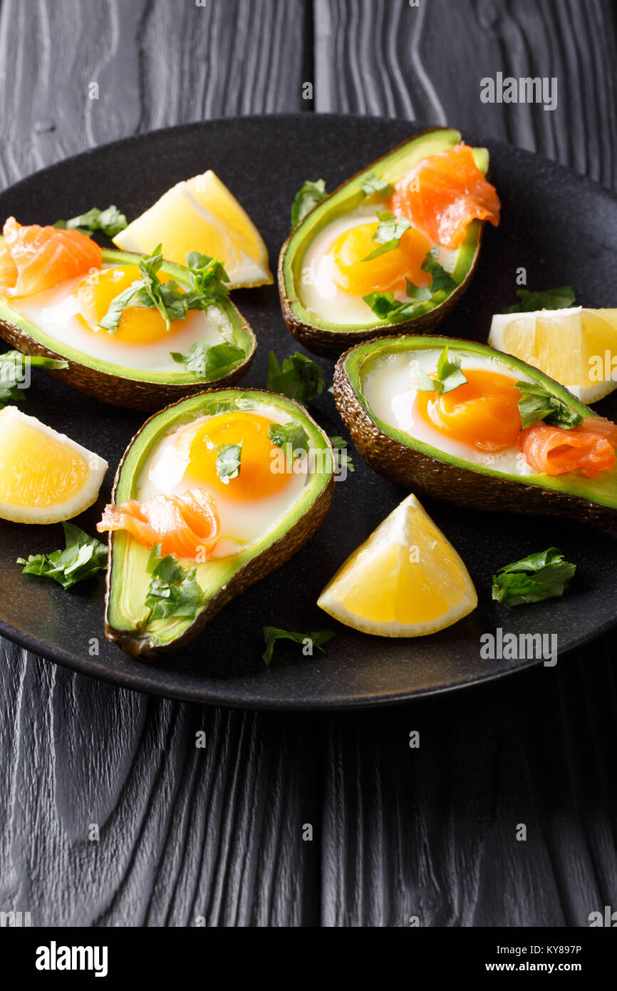 Gesundes Essen gebackene Avocado gefüllt mit Ei und rote Fische closeup auf einem Teller. Vertikale Stockfoto