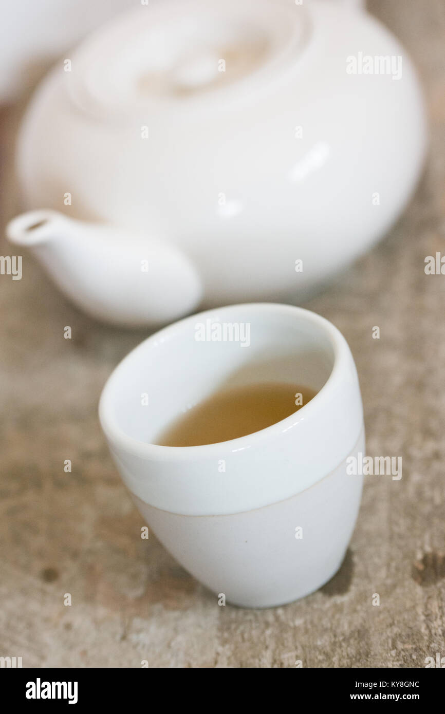 Weiß Teetasse und Teekanne mit greentea und rustikalen Holzmöbeln Hintergrund Stockfoto