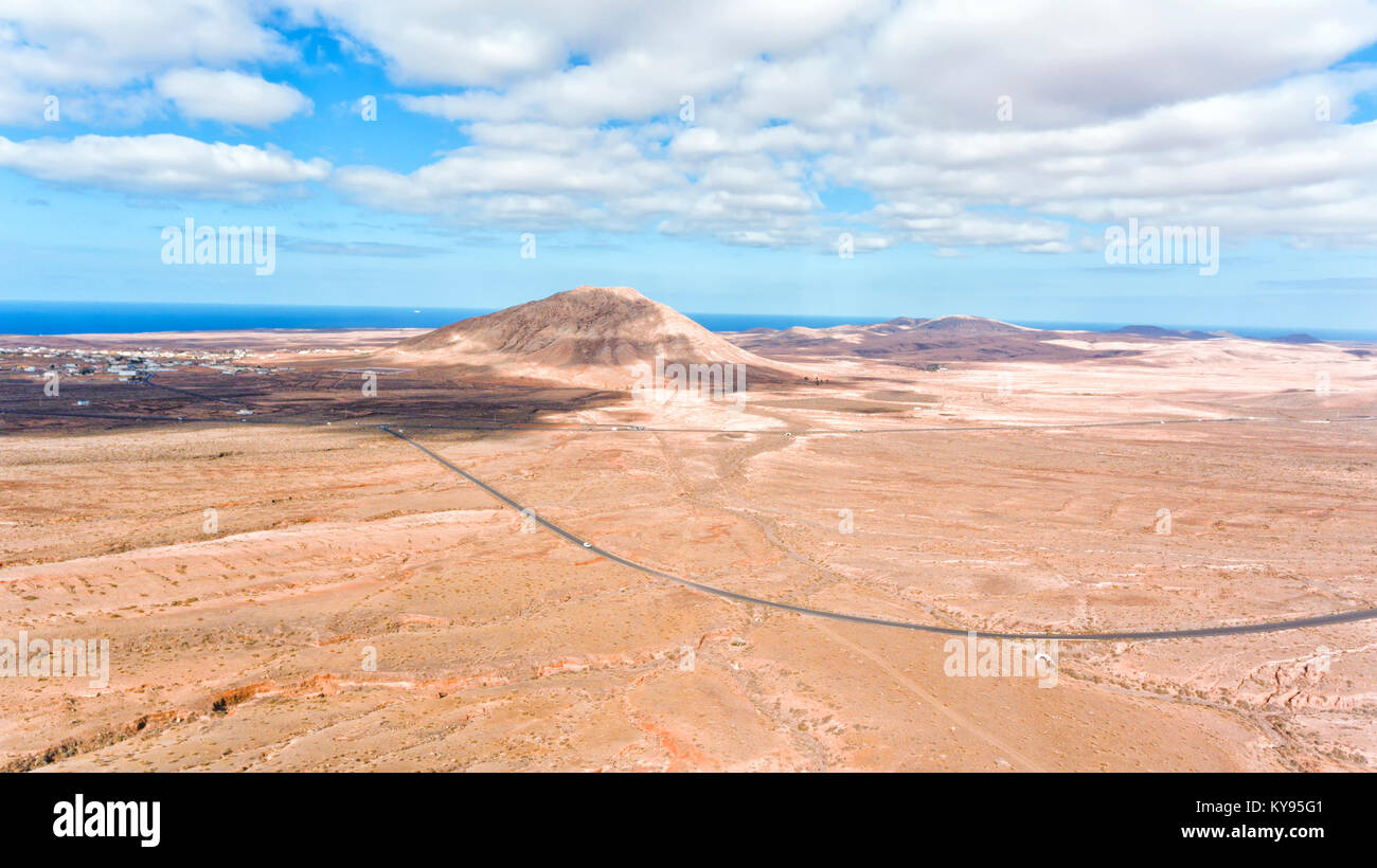 Luftaufnahme der Wüste Tal mit einem Vulkan peak in der Nähe von Sea Shore, Kreuzung open space, Fuerteventura, Kanarische Inseln, Spanien. Stockfoto