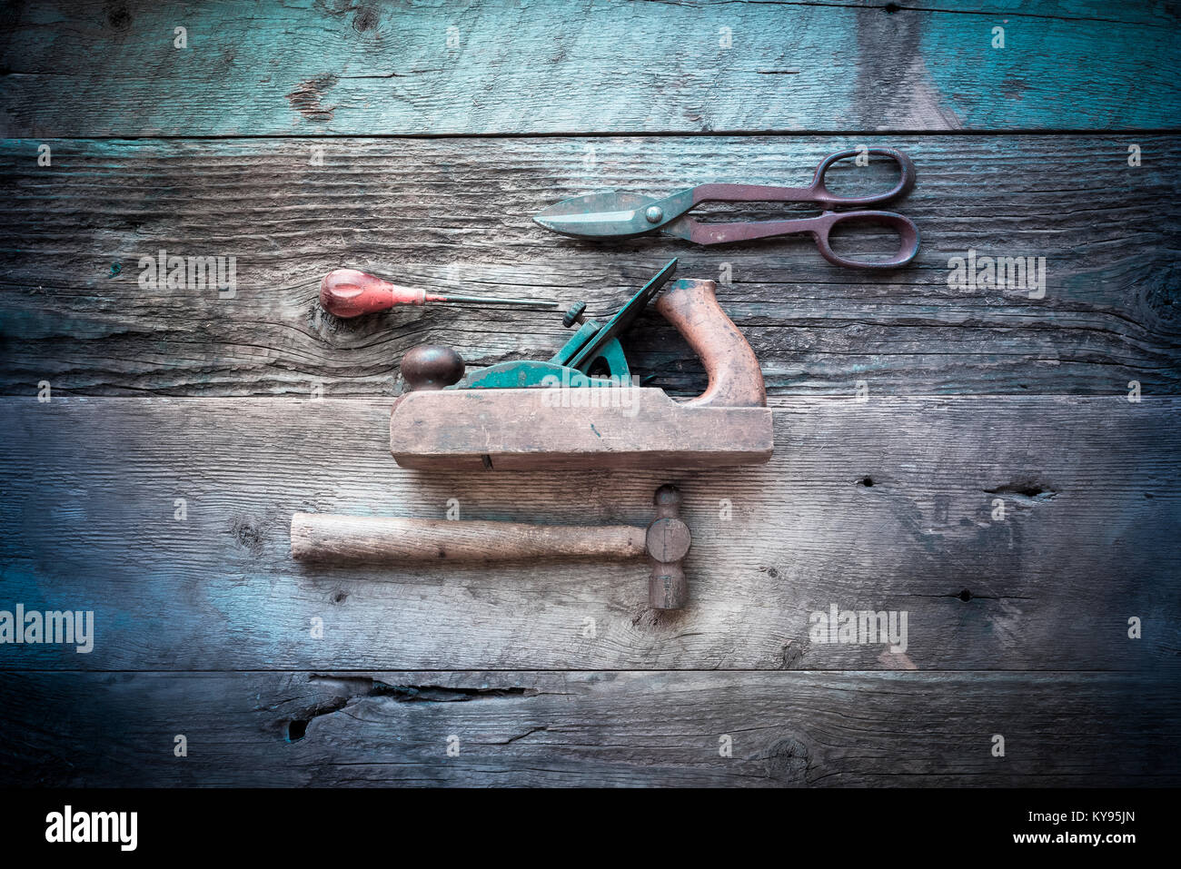 Overhead Bild der Sammlung von antiken, verwitterte vintage Tools, darunter Hammer, AWL, Zinn-schnitte und Holzklotz Ebene, gegen verwitterten Scheune Holz Stockfoto