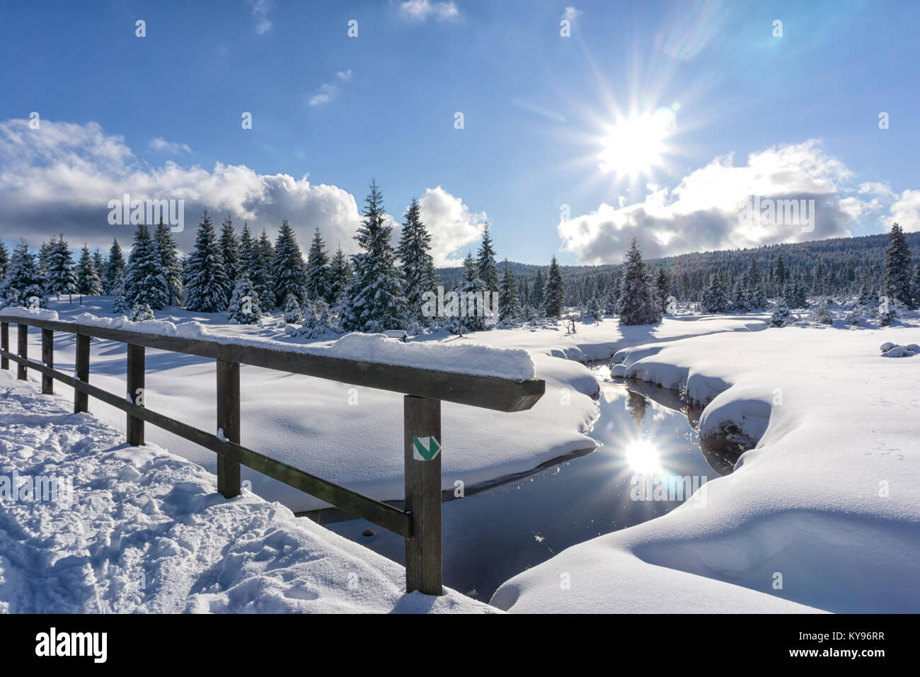 Winter Berglandschaft mit Stream und Holzbrücke. Bäume und die Sonne im Wasser spiegelt. Isergebirge, Tschechien, Europa. Stockfoto