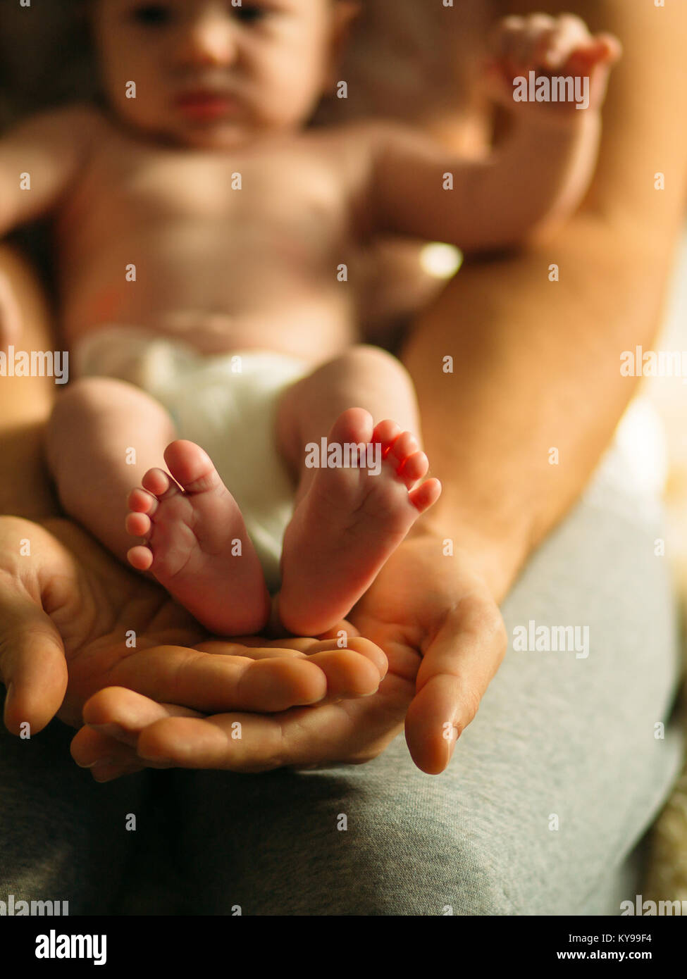 Neugeborenes Baby Beine in Mütter schöne Hand mit weichen Fokus auf und Schuhen Fuß Stockfoto