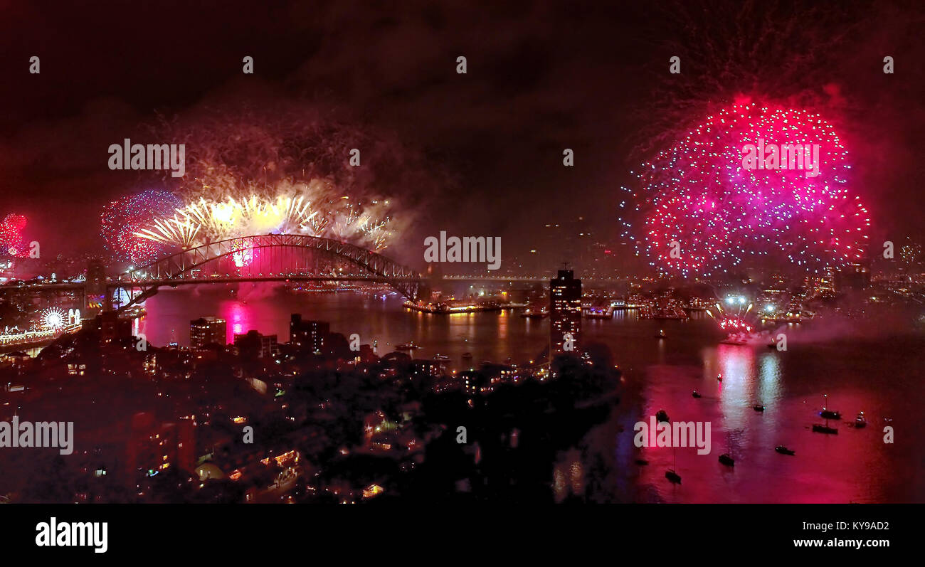 Helles Licht und Feuer Kugeln formen während Sydney das Neue Jahr Feuerwerk über Innenstadt Sehenswürdigkeiten am Ufer des Hafens von Sydney bei Nacht. Stockfoto