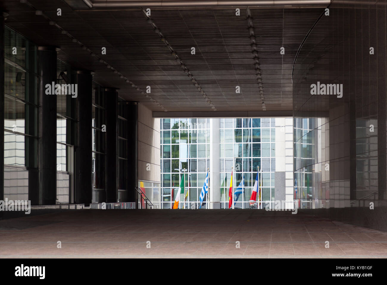 Die Gebäude des Europäischen Parlaments in Brüssel, Belgien, mit vielen europäischen Flaggen durch einen Tunnel unter dem Hauptgebäude gesehen. Stockfoto