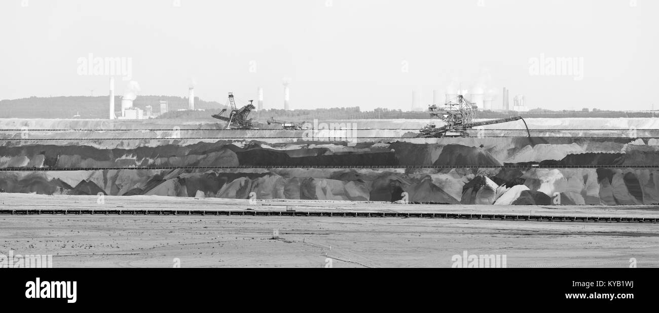 Panoramablick über einen großen braunkohletagebau Mine mit Schaufelradbaggern und anderen großen Maschinen, zwei Braunkohlekraftwerke im Hintergrund. Bl Stockfoto