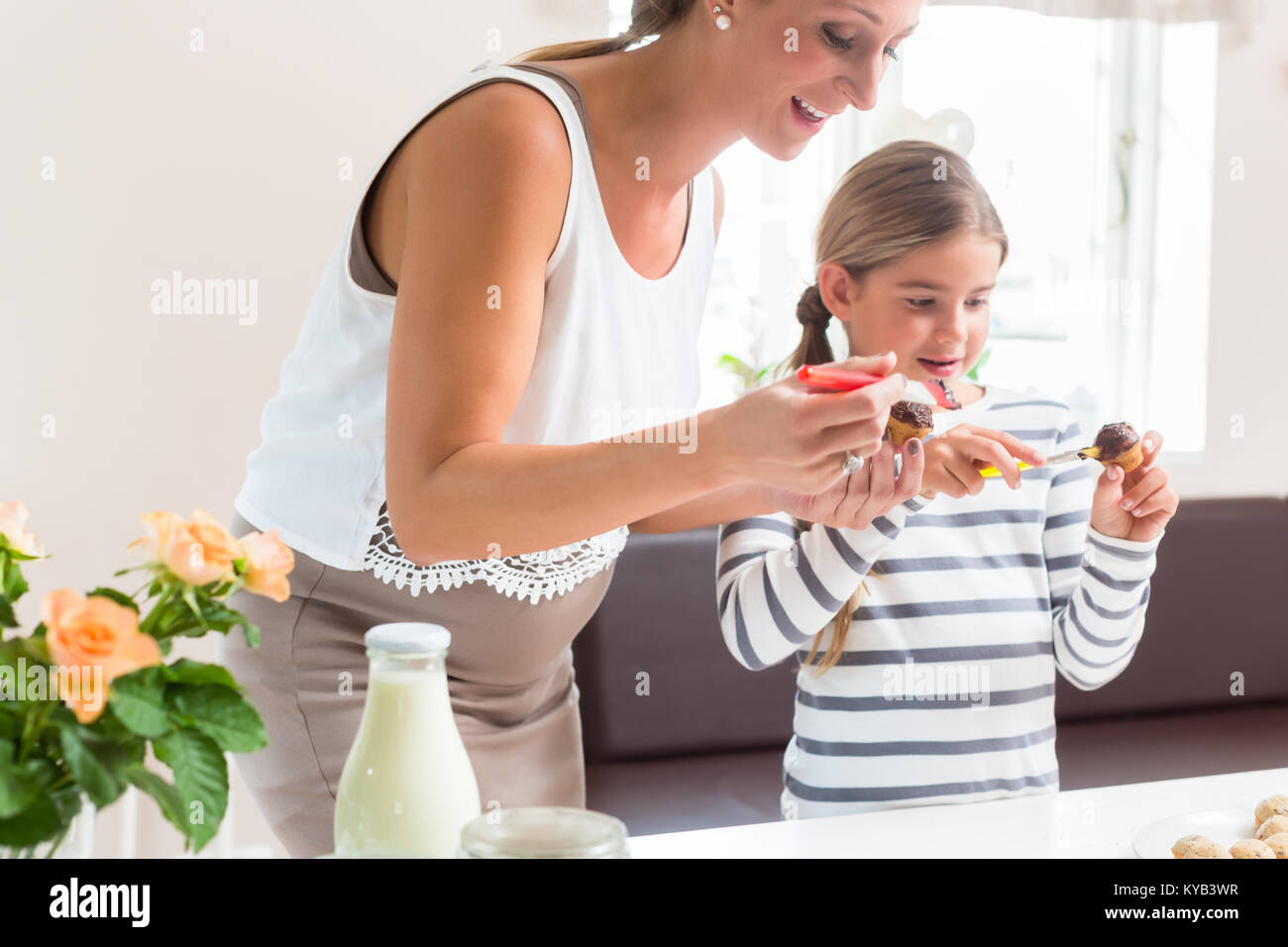 Schwangere Mutter backen Cupcakes mit Ihrer Tochter Stockfoto