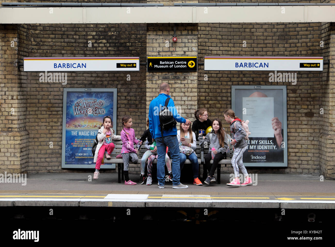 Gruppe von Mädchen mit einem Elternteil auf einen Tag warten, bis ein Zug auf dem Barbican Station u-Plattform im Herbst in London England UK KATHY DEWITT Stockfoto