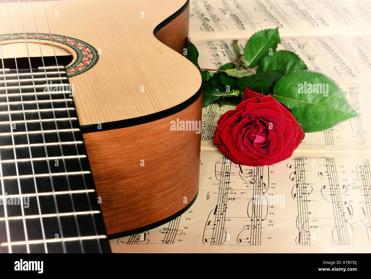 Rote Rosen, akustische Gitarre auf Noten als Hintergrund. Stockfoto