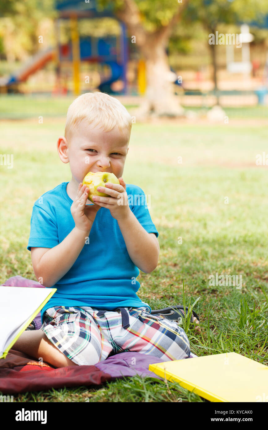 Little Boy Essen green apple mit Mimik Stockfoto